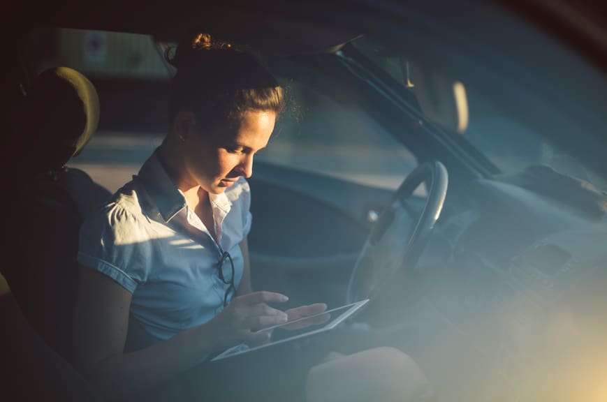 Woman in Car Reviewing Reasons to Refinance Her Car Loan.